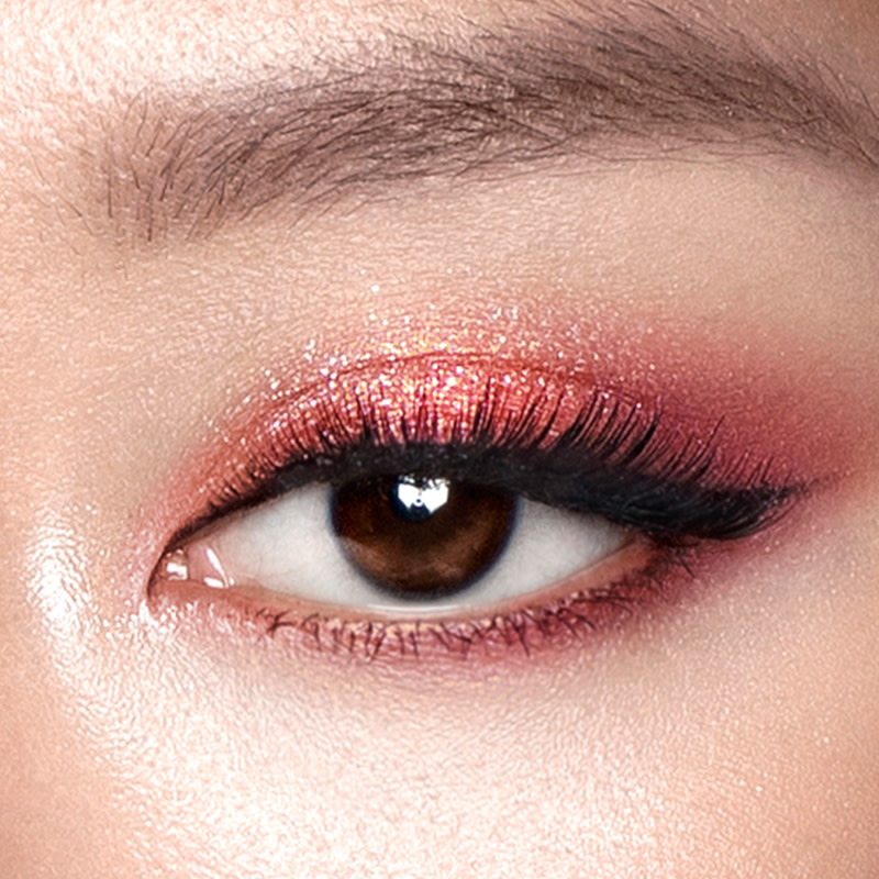 Eye close-up of a shimmery copper and muted red eye look on brown eyes. 