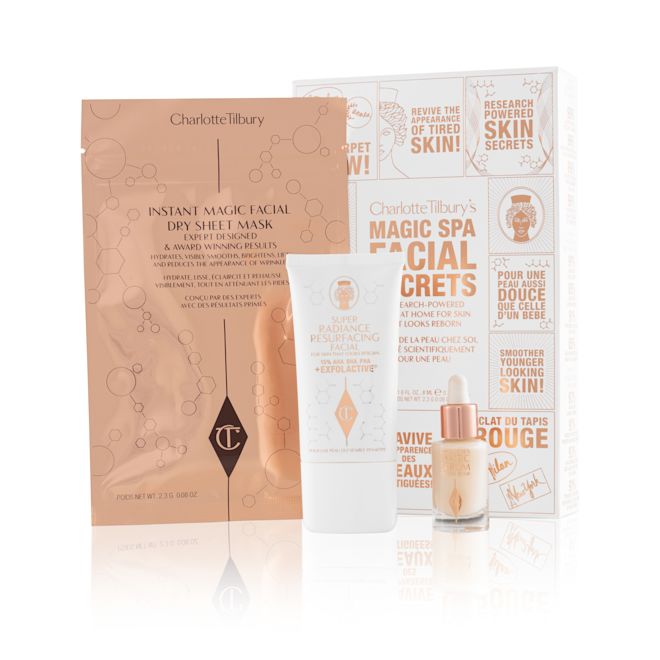 Magic Spa Facial Secrets displayed with packaging An elegant, white and gold skincare box with text in shiny gold colour that reads, 'Charlotte Tilbury's Magic Spa Facial Secrets' along with an exfoliating, wash-off mask in a white-coloured tube with a travel-size bottle of luminous face serum with a dropper lid, and a face mask in rose-gold-coloured foil packaging.