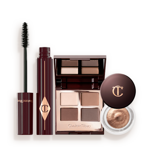 Bigger Brighter Eye Tricks Kit abierto Una paleta con cuatro sombras de ojos abierta con la tapa de espejo y tonos beige, marrón dorado, rosa dorado y rosa oscuro, una máscara de pestañas negra y una sombra de ojos en crema en un tono cobre dorado en un bote de cristal con la tapa de color marrón oscuro.