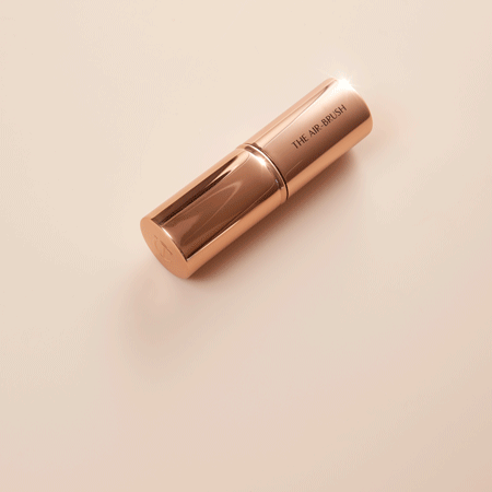 A GIF of a bronzer brush with soft cream-coloured bristles in shiny, metallic packaging. 