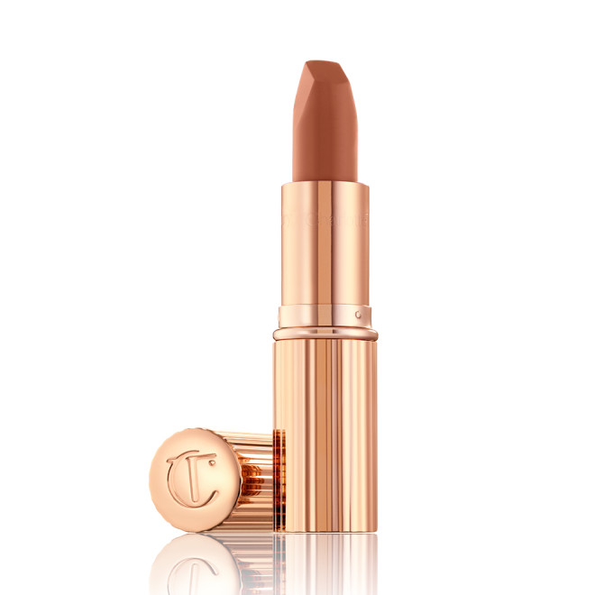 An open lipstick in a fresh, neutral nude peach matte shade, in a sleek, gold-coloured tube.