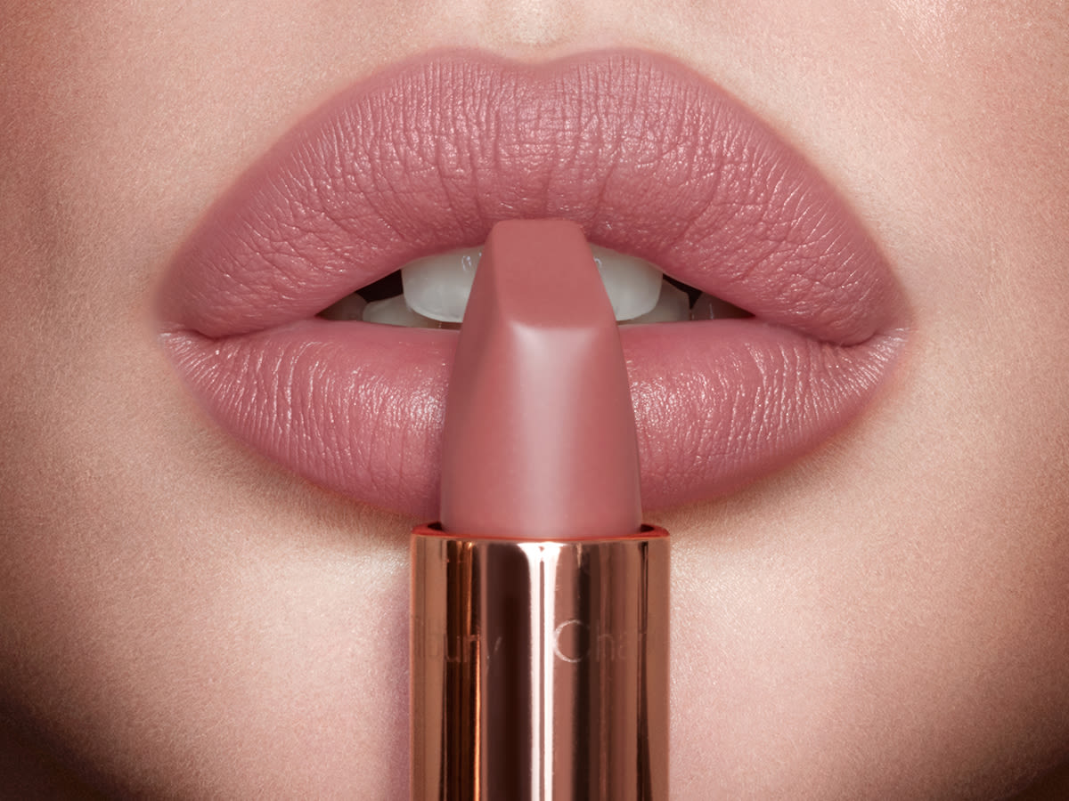 4x3 pillow talk matte rev peau claire lèvre close up Lips close-up of a light-tone model wearing a nude pink matte lipstick with the lipstick held in front of her lips.