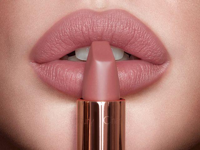 Matte Revolution in Pillow Talk on light tone model lips close-up Lips close-up of a light-tone model wearing a nude pink matte lipstick with the lipstick held in front of her lips.