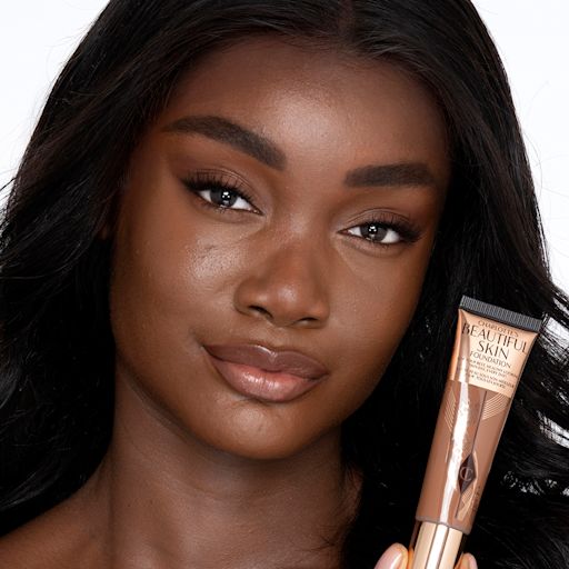 Beautiful Skin Foundation in 15N on a deep-tone model Deep-tone brunette model with brown eyes wearing nude pink lipstick with a skin-like foundation with a flawless, dewy finish.