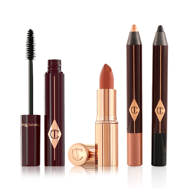 Smokey Eyes Stoned Rose Lips Kit open Black mascara in an open plum-coloured tube with its applicator next to it, an open coral lipstick in a gold-coloured tube, chubby eyeshadow stick in rose gold, and chubby eyeshadow stick in black.