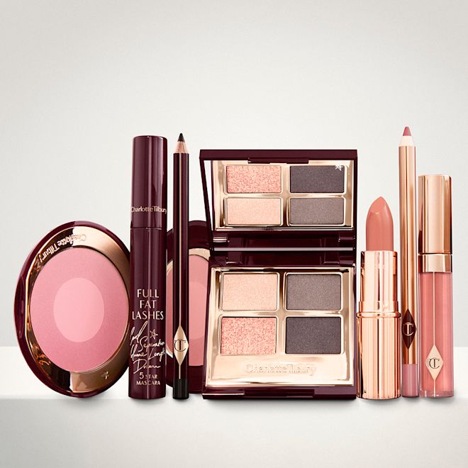 The Uptown Girl Look kit for light, fair and medium displayed An open, mirrored-lid eyeshadow palette in matte and shimmery gold and grey shades, an open black eyeliner pencil, a mascara in a dark-crimson colour scheme, a golden-peach lipstick with a matching lip liner pencil, coral lip gloss, and an open two-tone blush in cool pink.