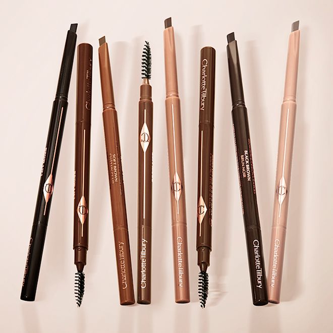 New Brow Lift Shades Cat Box ES A collection of double-ended eyebrow pencils and eyebrow brushes in shades of black, black-brown, light brown, medium brown, soft brown, dark brown, taupe, and light blonde.