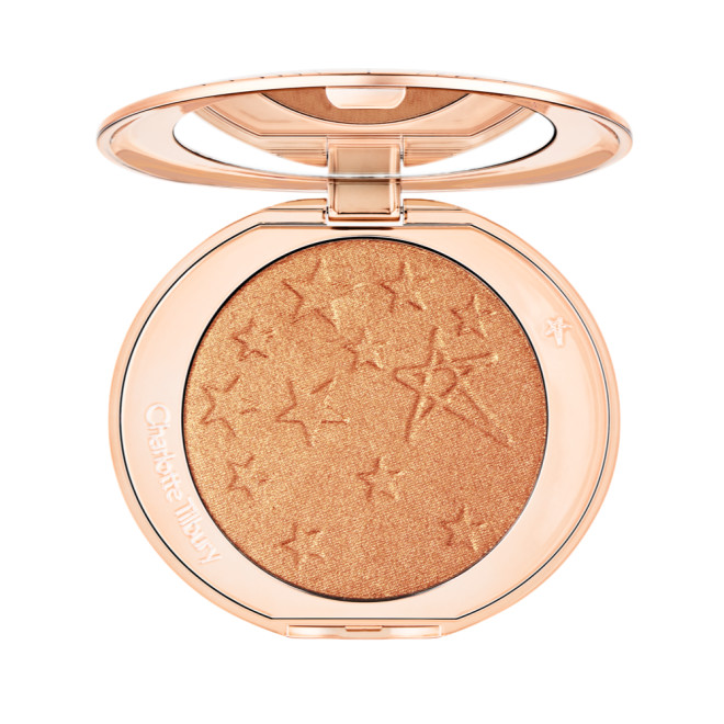 An open highlighter powder compact with a mirrored lid, in a shimmery copper-gold shade. 