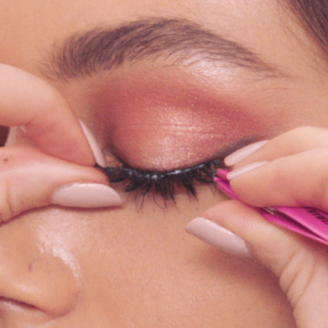 False Lash application Model applying false eyelashes lining them up with their lash line