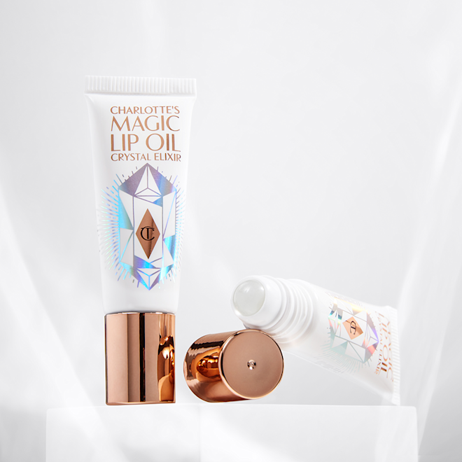 Lippenöl offen Two lips oil, one with its lid and one with the lid off, in white and rose gold packaging with shiny, geometric shapes on the tubes.