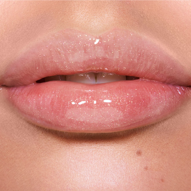 Lips close-up of a fair-tone model wearing a shimmery lip gloss in a rosy opal shade with fine glitter.