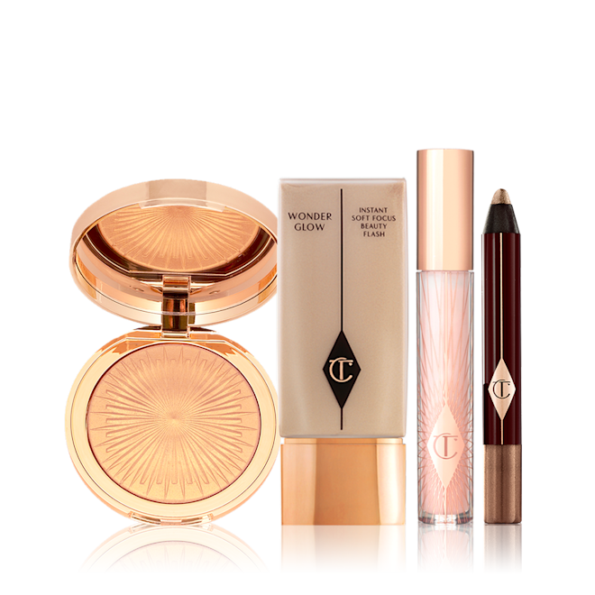 Summer is a feeling Bundle displayed A highlighter compact with a mirrored-lid in a warm golden colour, foundation in a light beige shade with gold-coloured lid, lip gloss in a sheer pink shade with light gold coloured lid, and chubby eyeshadow stick in a dark bronze shade.