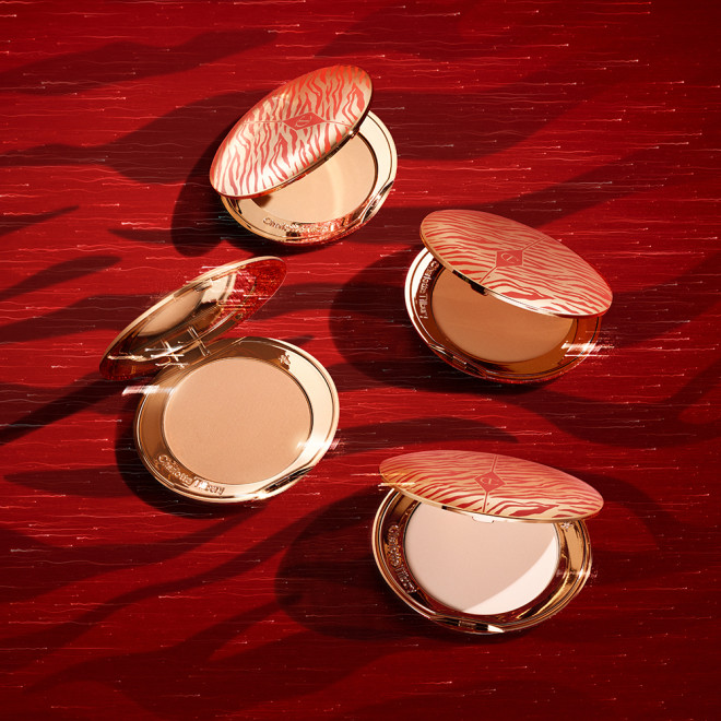 A collection of pressed powder compacts for light, medium-light, fair, and deep tones, in gold-coloured packaging with mirrored lids.