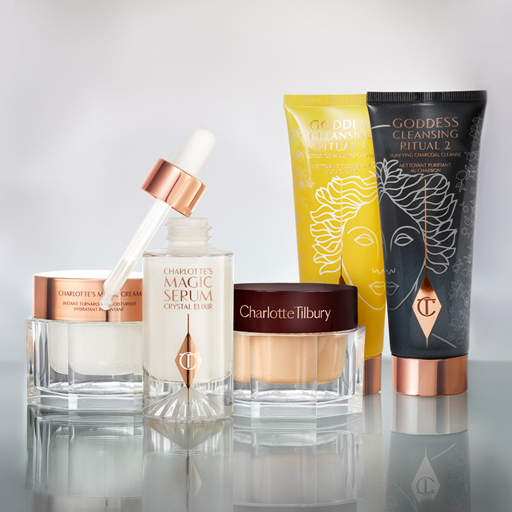 Pearly-white face cream and copper-coloured night cream in glass jars along with a luminous, ivory-coloured face serum in a glass bottle with a dropper lid, and two facial cleansers in lemon-yellow and charcoal-black-colorued tubes displayed.