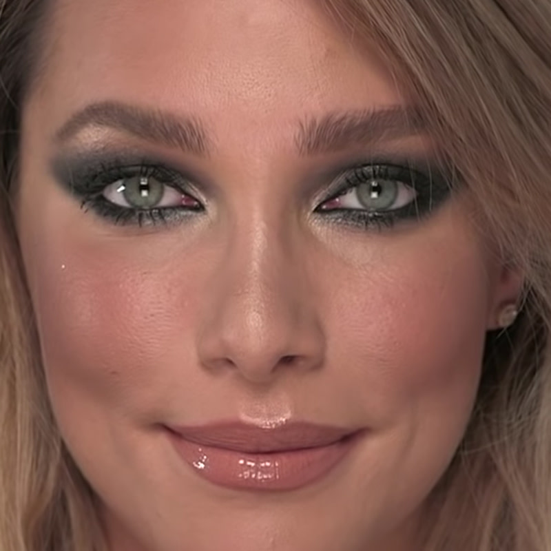 A light tone model with gray eyes with grey, smokey eye makeup and nude pink glossy lips. 