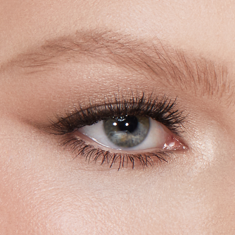 Single-eye close-up of a fair-tone model with grey eyes with fluffed out eyebrows in a light blonde shade.