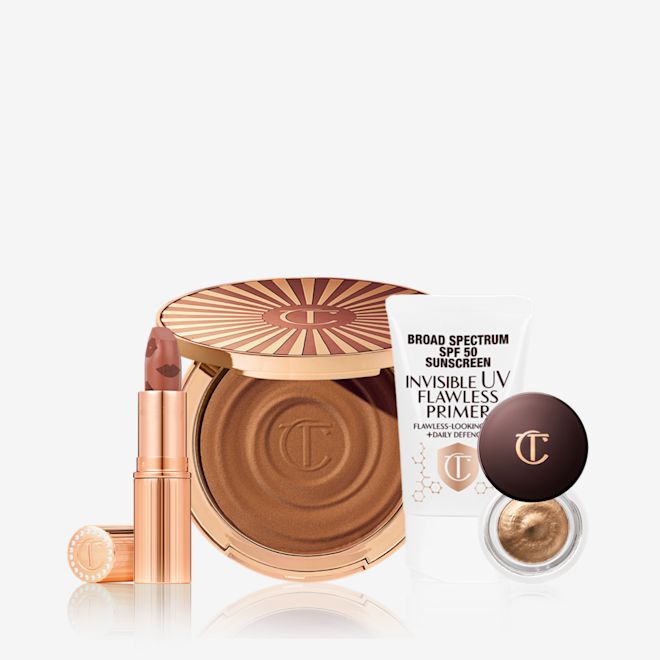 Full-Face-Of-Glow-Bundle-US An open nude terracotta lipstick in golden-coloured packaging, open cream bronzer compact in a dark brown shade, SPF-infused primer in white packaging, and cream eyeshadow in a dark gold shade with a dark brown lid.