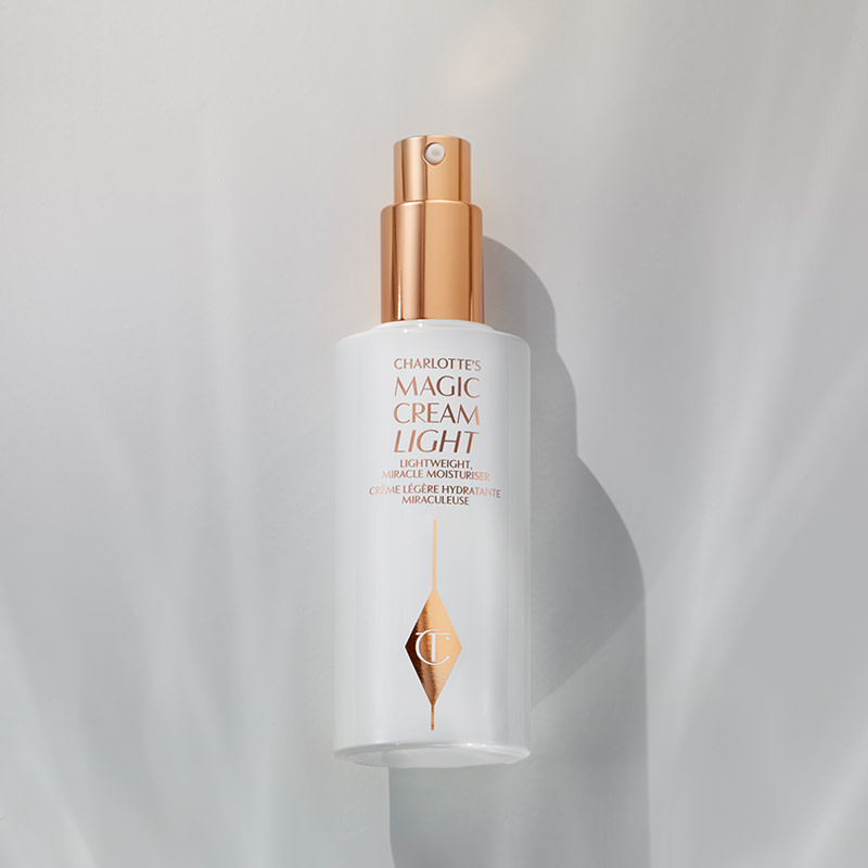 Face cream with its lid removed in a white and gold-themed clear bottle with a pump dispenser.