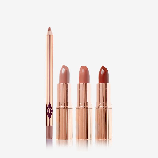 Super Nudes Lip Kit open An open lip liner pencil in a dark brown-beige shade with three open, nude lipsticks in cool-beige, nude peach, and nude brown-red, all four in gold-coloured packaging.