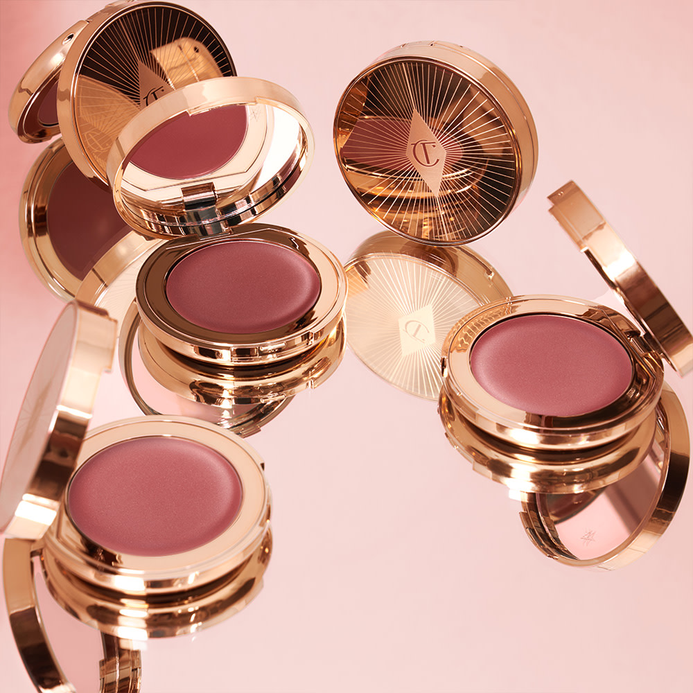 A collection of lip and cheek cream tints in berry-pink and peachy-pink shades in gold-coloured compacts with mirrored-lids. 