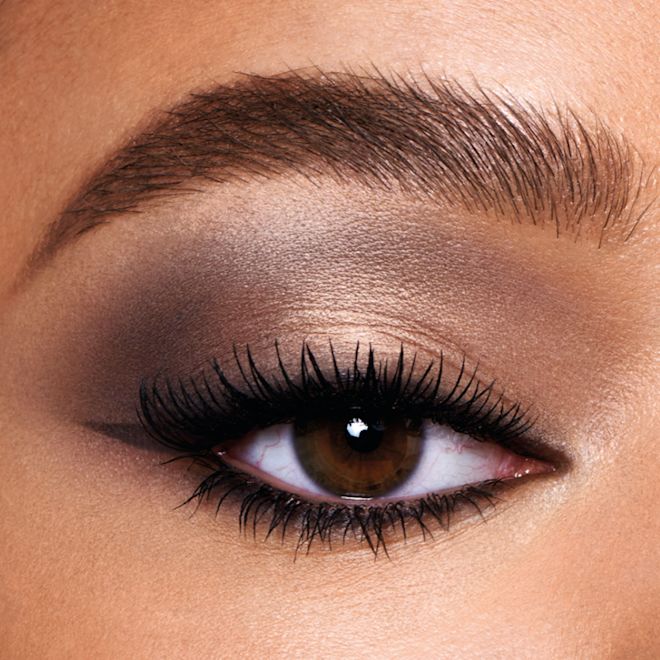 Super Nudes Easy Eye Palette cool nude eye look on brown eyes close-up Single-eye close-up of a medium-tone model with brown eyes wearing a smokey grey, light brown, and gold eye look with black wing eyeliner.