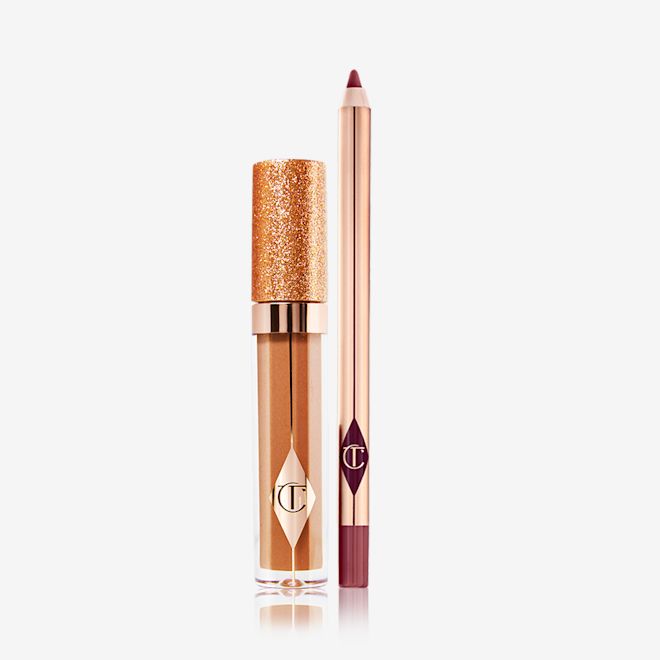 Jewel Lip Cheat Kit displayed A shimmery Lip gloss in a bronze-gold shade in a glass tube with a glittery lid with a lip liner pencil in a dark winter berry shade.