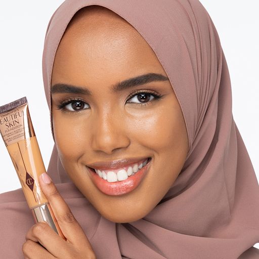 Beautiful Skin Foundation in 10W on deep-tone model Dark-tone hijabi model wearing glowy, skin-like foundation with a satin finish with nude lipstick and subtle eye makeup.