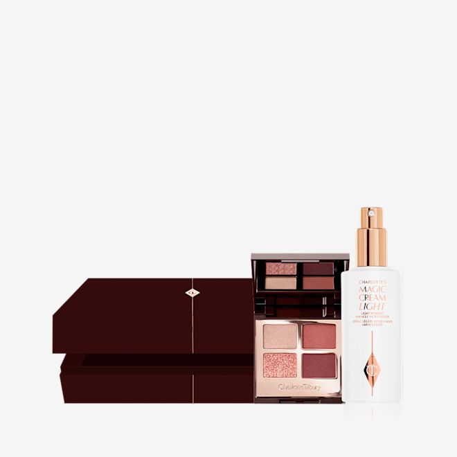 Beauty Secrets Mystery Box open An open, dark brown mystery gift box with an open, quad eyeshadow palette with a mirrored lid with eyeshadows in shades of russet rose, dark brown, rose gold, and dull gold along with a face cream in a white-coloured bottle with a gold-coloured pump dispenser.