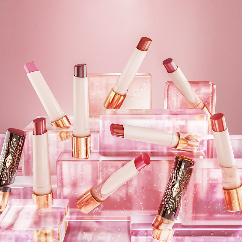 A collection of open, moisturising, high-shine lipstick balms in shades of red, pink, purple, brown, peach, and coral in white and gold-coloured tubes with black-coloured lids with gold-coloured stars printed all over.