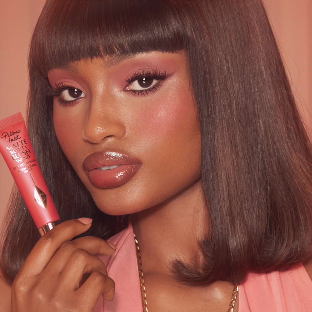 Model wearing Matte Beauty Blush Wand in Pillow Talk Dream Pop to give the cheeks a cherry red pop of colour