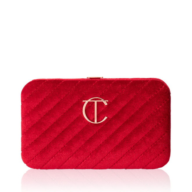 A closed, bright-red-coloured velvet brush clutch with the iconic CT logo on the front in gold.