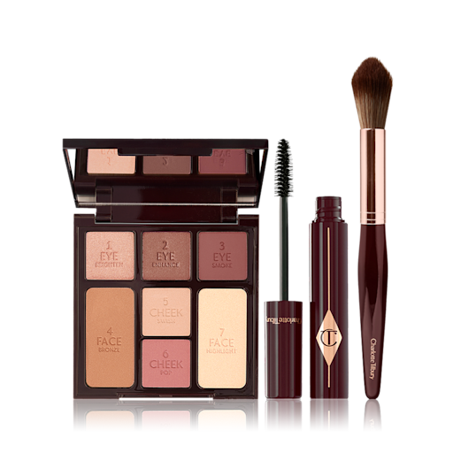 Gorgeous Glowing Makeup Kit open An open, mirrored-lid face palette with nude eyeshadows, blushes, bronzer, and highlighter with an open mascara and blending brush in dark crimson colour.