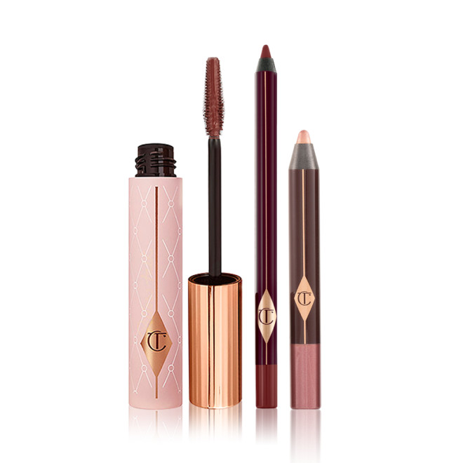 An open berry-brown mascara in a nude pink tube with a gold-coloured lid, eyeliner pencil in dark brown, and chubby eyeshadow stick in rose gold.