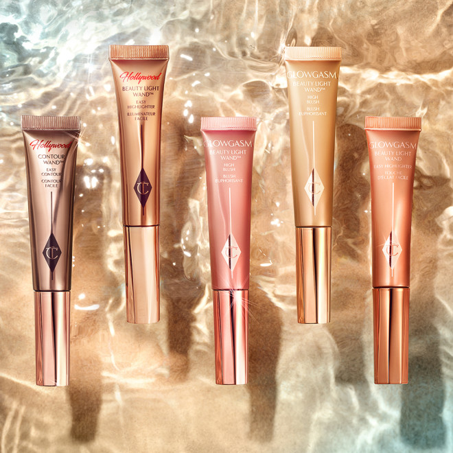 A collection of blush and highlighter wands and contour wand in shades of honey-gold, rose gold, warm pink, nude pink, coppery-gold, and dark contour shade.