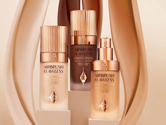 Airbrush Flawless Foundations Three foundations in fair, medium, and dark shades with frosted glass bottles and rose-gold-coloured pumps and lids.