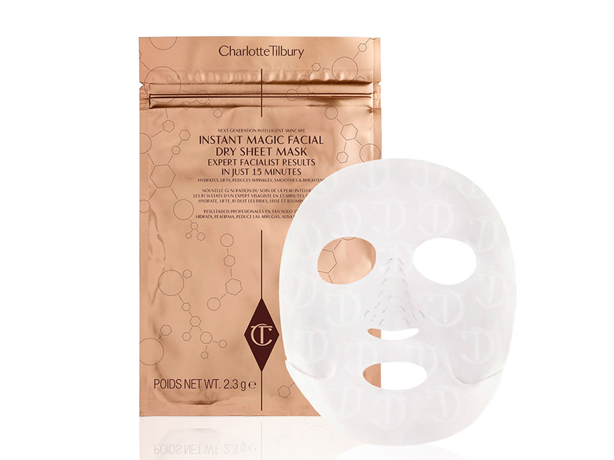 Instant Magic Facial Dry Sheet Mask open A hydrating face sheet mask in textured fabric with its gold-coloured foil packaging behind it.