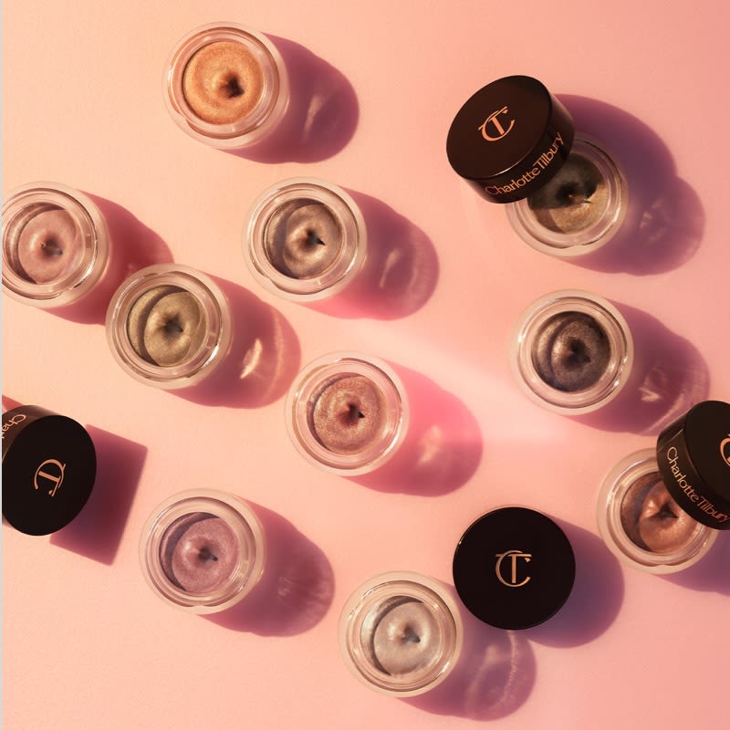 Eyes to Mesmerise Banner Banner with a collection of cream eyeshadow pots with metallic finishes in shades of pink, golden, silver, grey, copper, and brown.