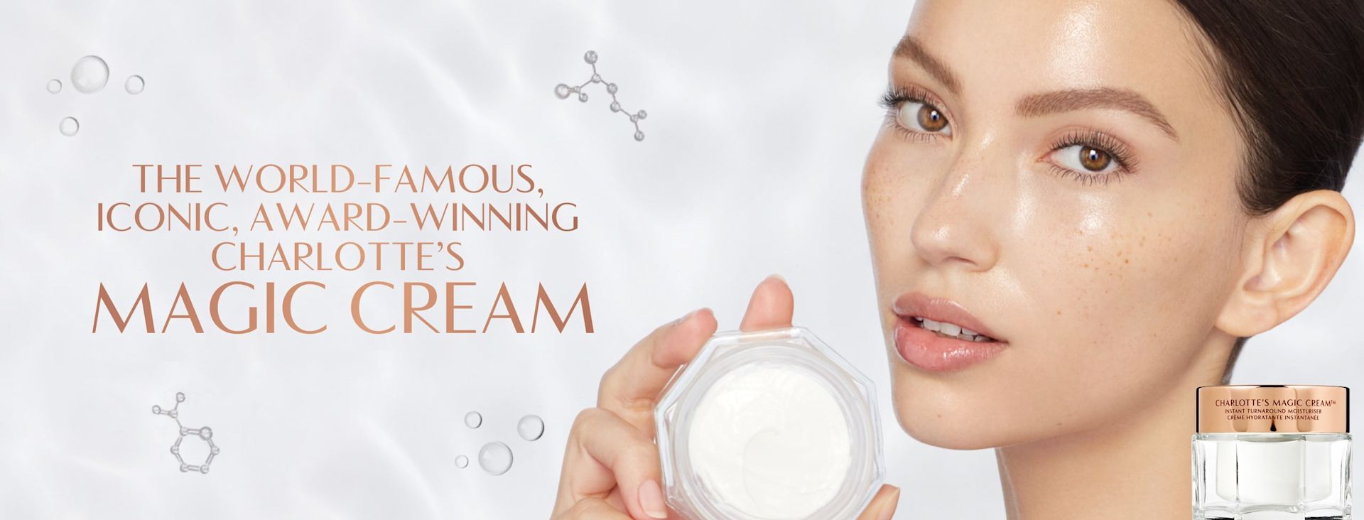 Magic Cream banner Banner with a fair-tone brunette model with brown eyes and glowy, flawless skin holding up an open jar of pearly-white face cream, with text on the banner that reads, 'The world-famous iconic, award-winning Charlotte's Magic Cream'