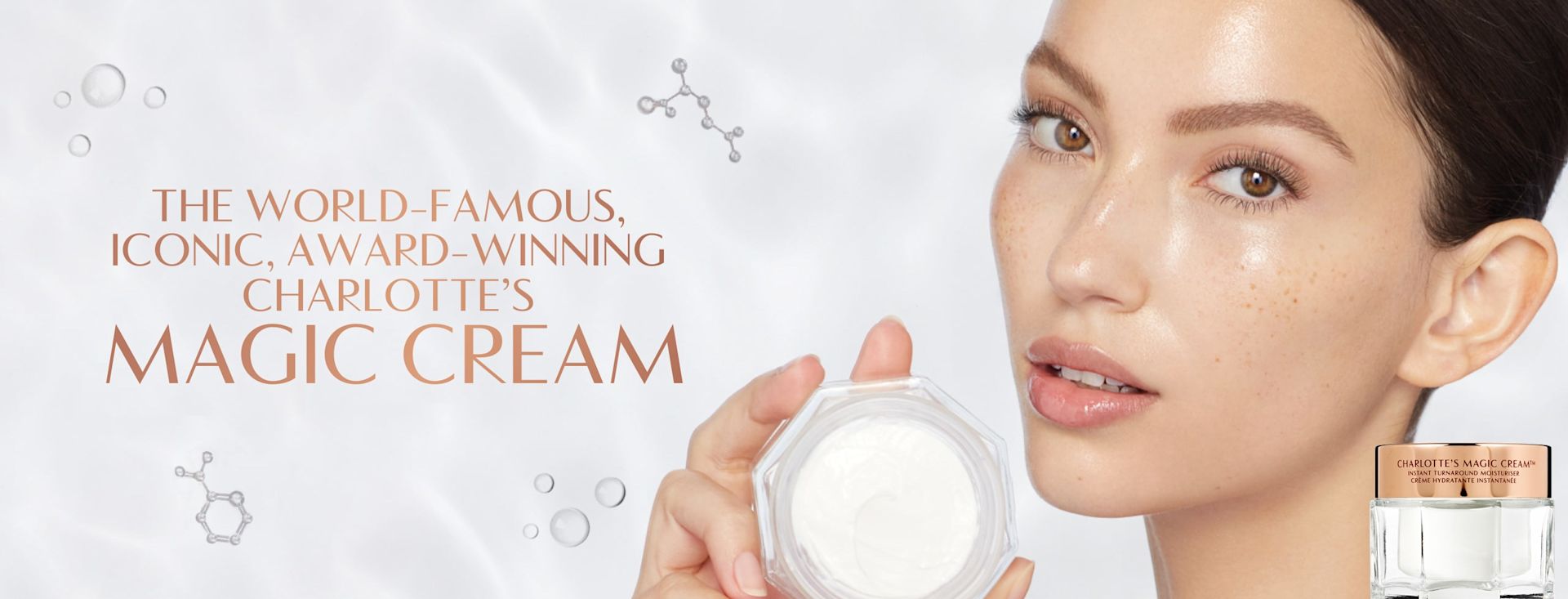 Magic Cream banner Banner with a fair-tone brunette model with brown eyes and glowy, flawless skin holding up an open jar of pearly-white face cream, with text on the banner that reads, 'The world-famous iconic, award-winning Charlotte's Magic Cream'