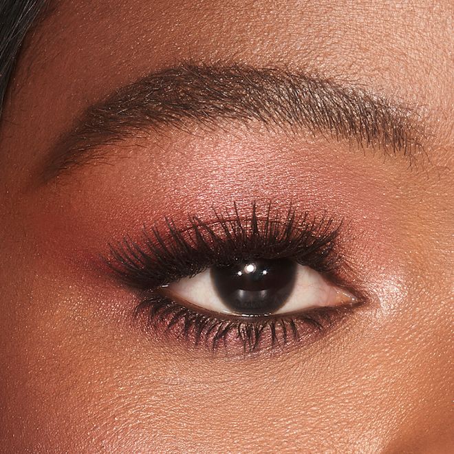 Luxury Palette in Walk of No Shame on brown eyes close-up Single-eye close-up of a brown-eyed deep-tone model wearing shimmery berry-pink eye makeup.