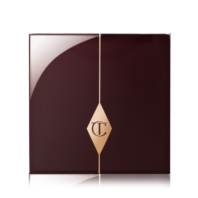 A closed eyeshadow palette with dark crimson packaging with the CT logo printed in the middle in a gold-colour.