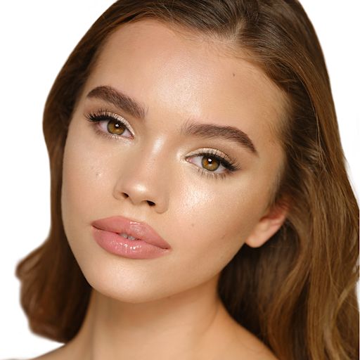 Hollywood Highlighter in Champagne Glow on medium-tone model Medium-tone brunette model wearing glowy highlighter in a champagne-gold shade with nude pink lip lipstick and soft eye makeup.