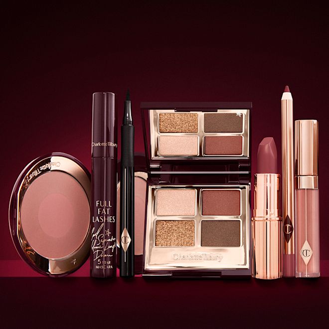 The Bella Sofia Makeup kit for deep tones open An open, mirrored-lid eyeshadow palette in matte and shimmery brown and gold shades, an open black eyeliner pen, a mascara in a dark-crimson colour scheme, a berry-rose lipstick with a matching lip liner pencil, nude pink lip gloss, and an open two-tone blush in warm pink.