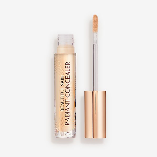 Beautiful Skin Radiant in Concealer in 4.5 lid removed Radiant concealer in a glass tube with its doe-foot applicator next to it with a gold-coloured handle.