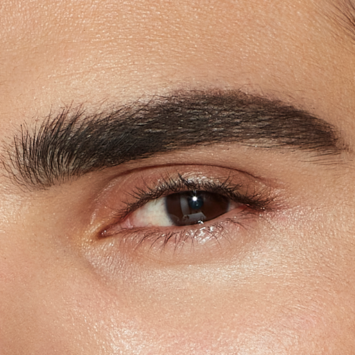 Legendary Brows in Black Brown on model with brown eyes close-up Single-eye close-up of a male model with brown eyes and thick, shaped, and filled eyebrows in a blac-brown colour.