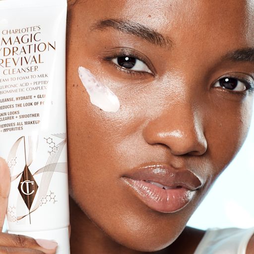 Magic Cleanser 3-in-1 Model applying Charlotte's Magic Hydration Revival Cleanser to their cheek