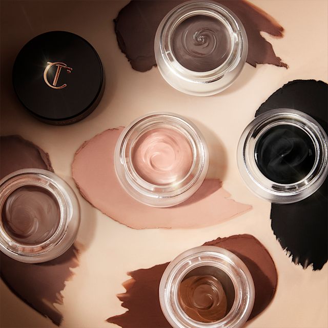 Matte Eyes to Mesmerise collection open Five, glass pots with lids removed containing five cream eyeshadows with a matte finish in soft cashmere, light grey-brown, chocolate brown, smokey taupe, and jet black.