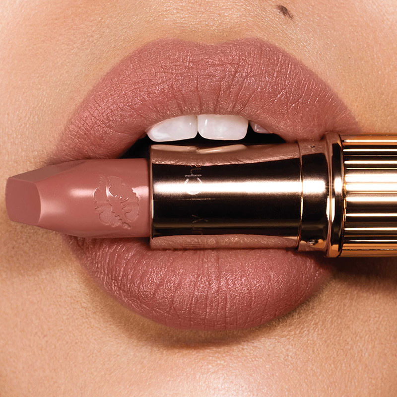A light-tone model wearing a nude, brownish-pink coloured lipstick that makes teeth look whiter. 