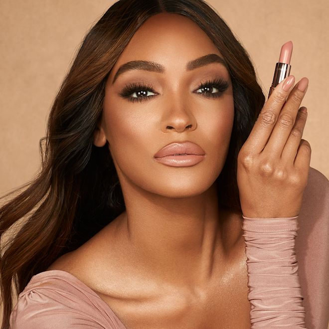 K.I.S.S.I.N.G. in Runway Royalty on deep-tone model Deep-tone brunette model with brown eyes wearing lipstick in a soft rosy peach shade with a satin finish and black eyeliner.