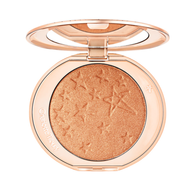 An open highlighter powder compact in a soft rose gold shade with a mirrored lid.